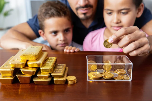 un père et ses deux enfants avec des lingots et pièces d'or d'investissement sur une table