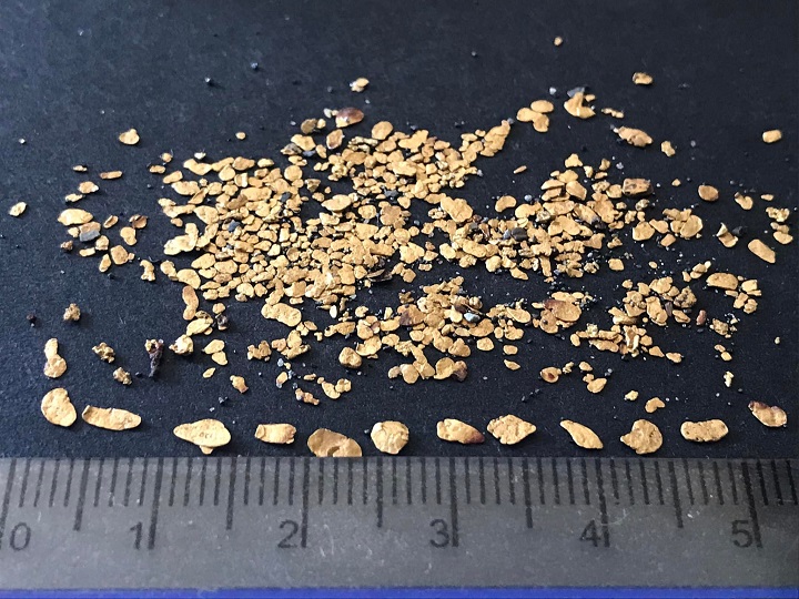 ensemble de paillettes d'or présenté devant une règle millimétrée