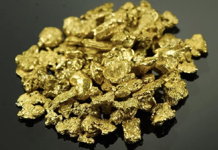 ensemble de pépites et de paillettes d'or posé sur une table noire